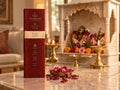 Rose Dawn incense box placed on a marble table before a temple altar, with a bowl of dried rose petals